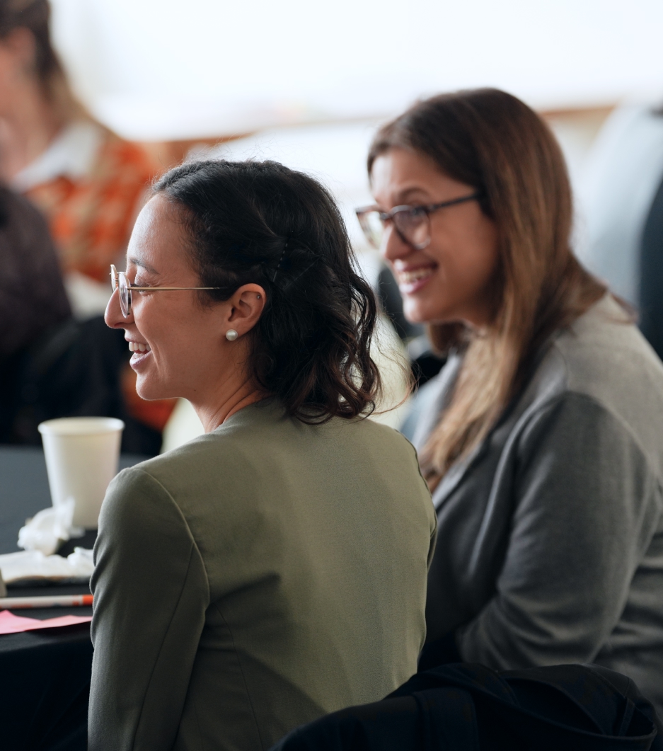 Two professional women laughing at a conference table