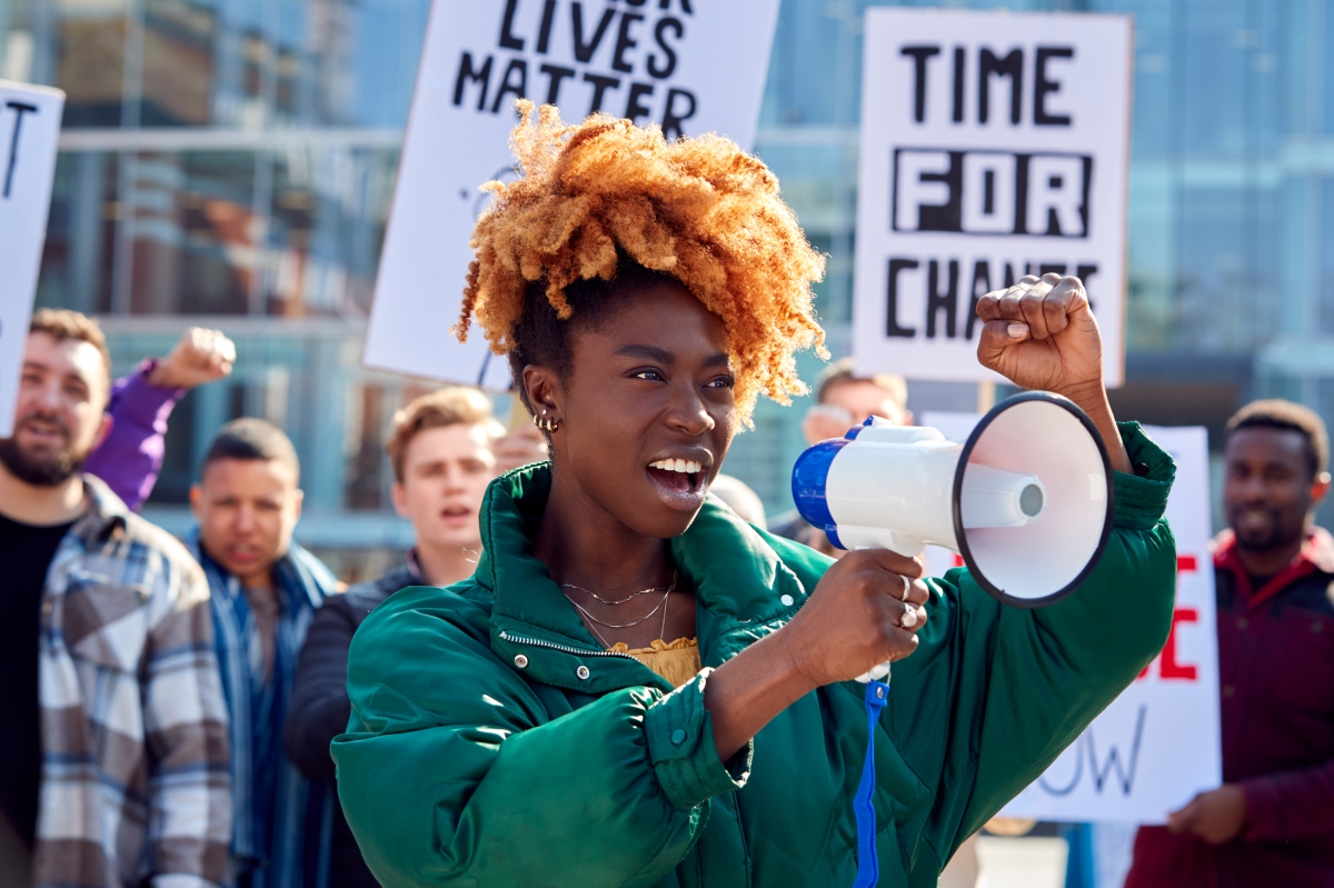 Black woman with bright red hair looking passionate at a black lives matter protest