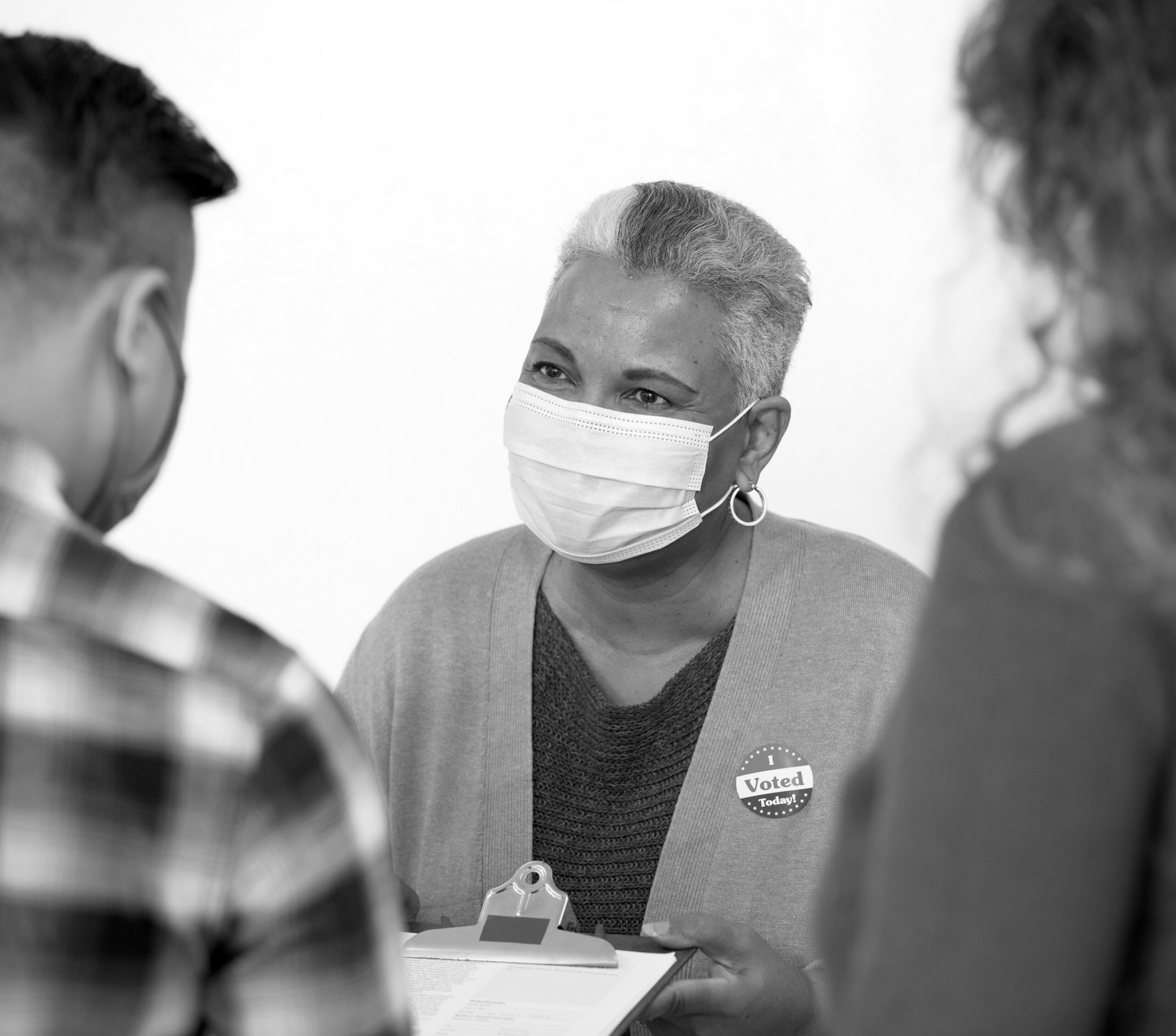 Election poll worker with a mask on helps others vote