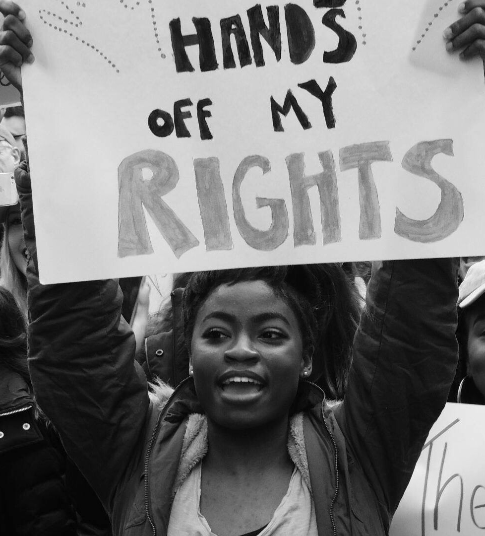 Young black woman with protest sign reading 'hands off my rights'