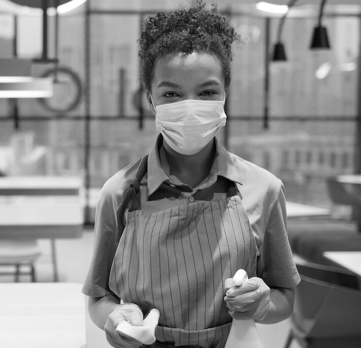 young woman working in a coffee shop with a mask on